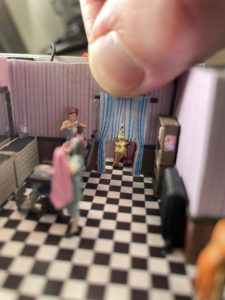 A fourth customer sits patiently in the waiting area beyond the curtain.