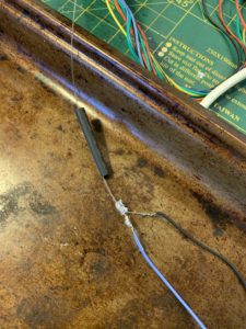 This LED has a tiny hole drilled in its dome with a fiber optic filament glued into it, which illuminates the flickering TV screen. Black heat shrink tubing contains the light from the LED beneath the scenes.